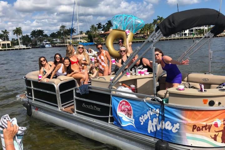 Group of people partying on a boat with decorations in sunny weather.
