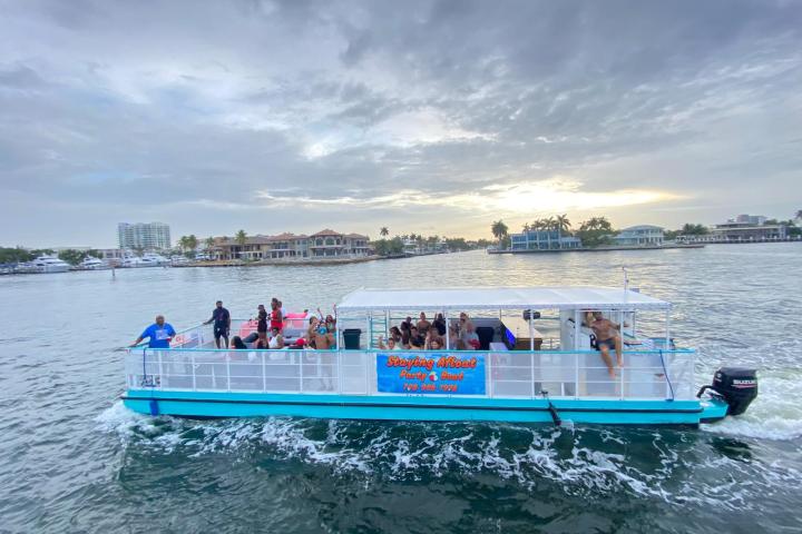 Tourists on a blue and white boat in a scenic waterway at sunset.