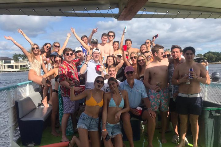 Group of people on a boat celebrating under a cloudy sky.