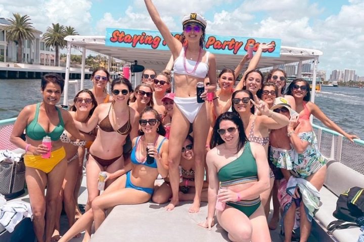 Group of women in swimwear celebrating on a boat in sunny weather.
