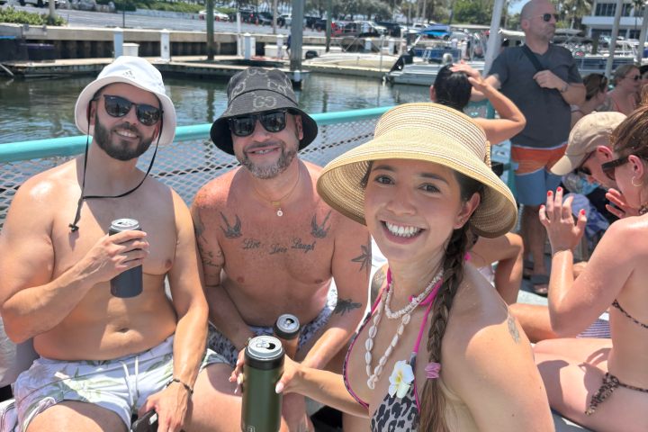 People in swimwear on a boat holding drinks on a sunny day.